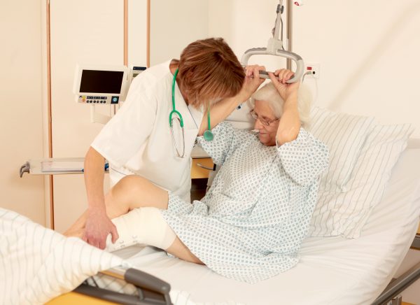Krankenschwester hilft Patientin aus dem Bett