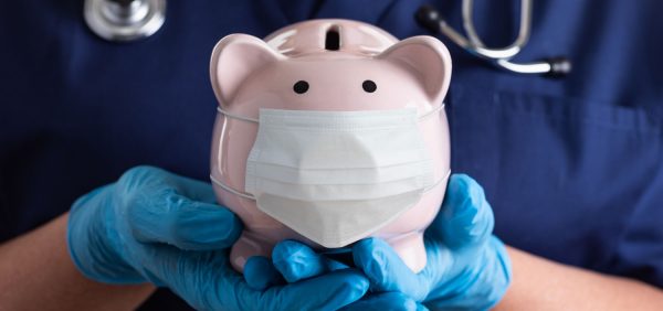 Sonderprämie: Pflegekraft hält Sparschwein mit Mundschutz