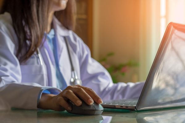 Ärztin nimmt über Laptop digital Kontakt zu Patient auf
