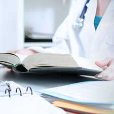Ärztin blättert in einem Medizinbuch