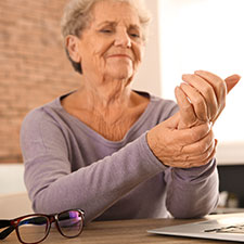 Eine Seniorin greift sich ans schmerzende Handgelenk