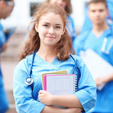 Eine junge Medizinstudentin mit Lernunterlagen im Arm, im Hintergrund ihre Kollegen