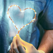 Ein Mediziner mit Einmalhandschuh hält ein leuchtendes Herz