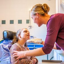 Pflegerin kümmert sich um ein Mädchen im Rollstuhl