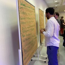Teilnehmer schreiben Verbesserungswünsche auf Stellwände
