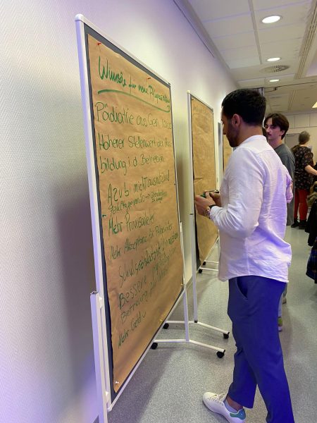 Teilnehmer schreiben Verbesserungswünsche auf Stellwände