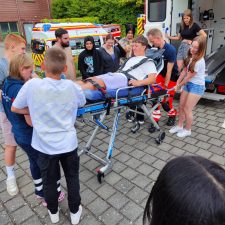 Schüler und Schülerinnen schieben einen Mitschüler auf einer Fahrtrage in einen Rettungswagen