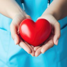 Hände halten ein rotes Herz zur Wertschätzung der Angestellten im Gesundheitswesen.