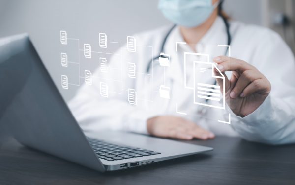 Medizinsiche Fachkraft sitzt am Laptop und wählt virtuelle Dokumente aus