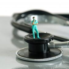 Männliche Minifigur eines Krankenpflegers steht auf Stethoskop