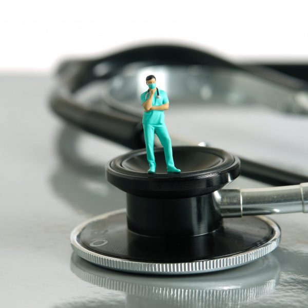 Männliche Minifigur eines Krankenpflegers steht auf Stethoskop