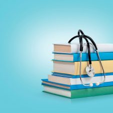 Bücherstapel auf dem ein Stethoskop liegt.
