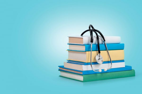Bücherstapel auf dem ein Stethoskop liegt.